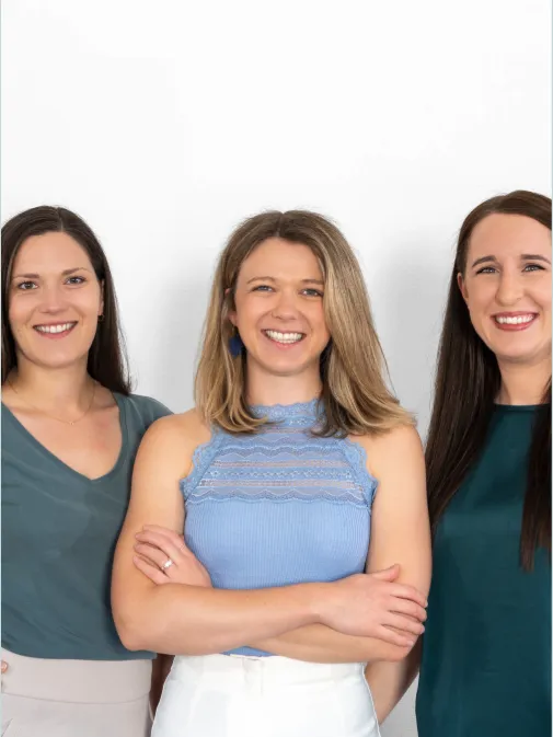 Teamfoto von Kommunikana mit drei Mitarbeiterinnen vor hellem Hintergrund. Die Aufnahme vermittelt Professionalität, Vertrauen und eine persönliche Zusammenarbeit im Bereich Social Media und Kommunikation.